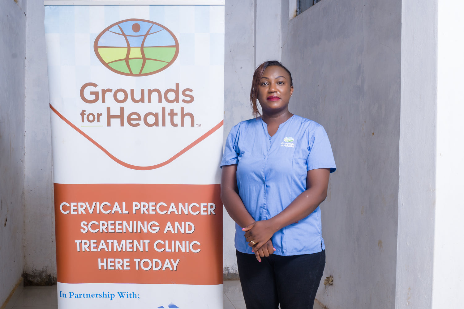 Image of medical worker next to Grounds for Health signage.